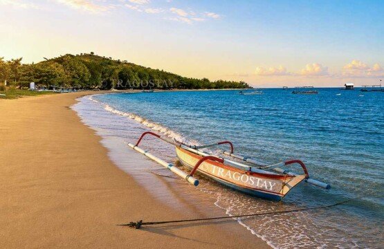 A colorful traditional Balinese outrigger fishing boat resting on the calm waters of the beautiful Pemuteran Beach holiday destination.
