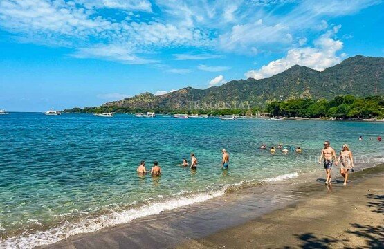 A group of cheerful holidaymakers chatting, walking, and soaking up the wonderful coastal atmosphere at Pemuteran Beach.