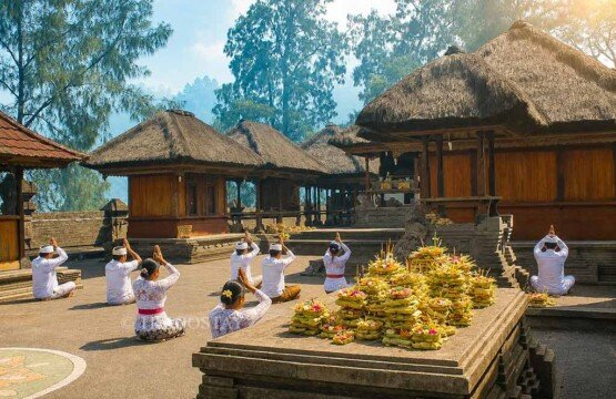 A group of Balinese Hindu worshipers in traditional dress sitting on the ground during a communal prayer ceremony at Puncak Penulisan Temple.