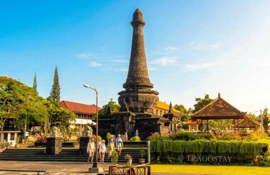 The scenic grounds of the Puputan Klungkung Monument being explored by travelers on a clear morning.