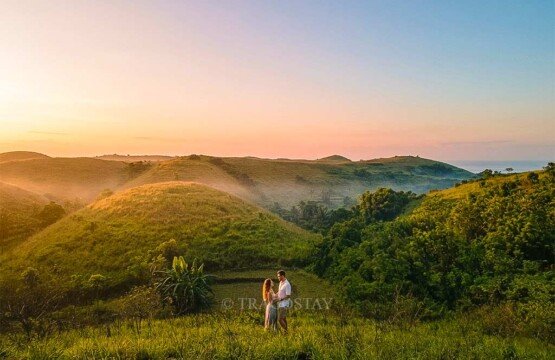 A romantic couple standing together during a golden sunrise at the scenic Teletubbies Hill viewpoint.
