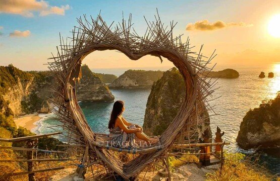 A female tourist sitting inside a heart-shaped wooden nest overlooking the beauty of Thousand Islands Viewpoint.