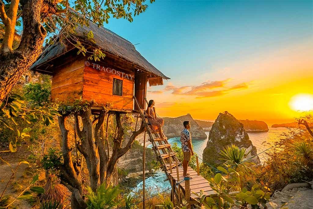 Two tourists sitting and standing in front of the famous wooden treehouse at Thousand Islands Viewpoint.