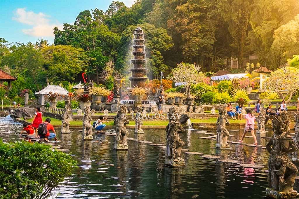 A huge fish pond at Tirta Gangga filled with golden koi fish and ornate stone statues.