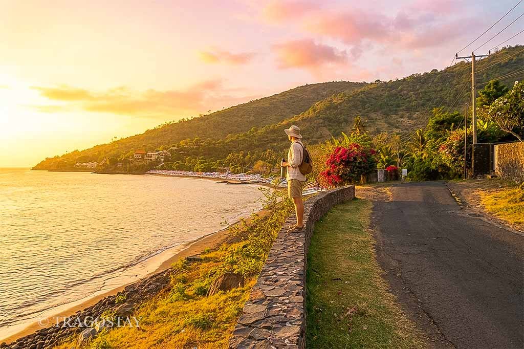 A tourist relaxing and enjoying the peaceful sunrise atmosphere on the pebble shores of Tulamben.