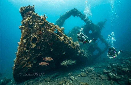 Two scuba divers navigating through the structural remains of the USAT Liberty Wreck in Tulamben.