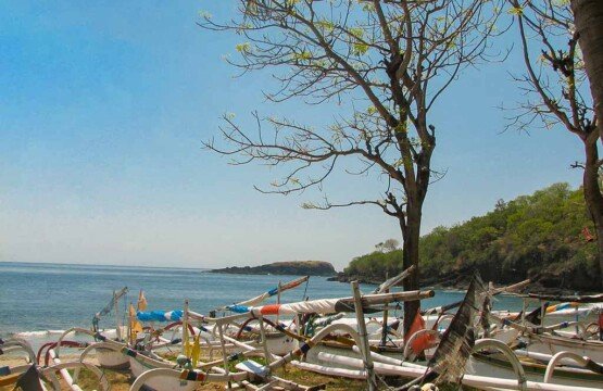 Numerous colorful traditional Balinese jukung boats anchored along the shoreline of Virgin Beach.
