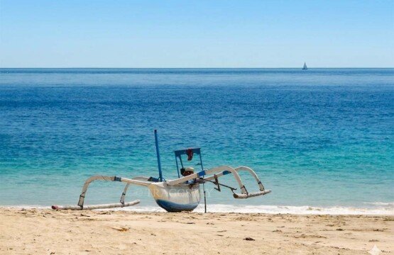 A traditional Balinese boat resting on the pristine white sand of Virgin Beach Karangasem.