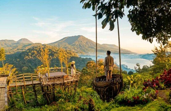 A tourist couple standing together on a wooden viewing platform at Wanagiri Hidden Hills, admiring the beautiful landscape during a clear afternoon.