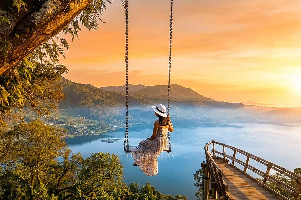 A tourist swinging on a high-altitude rope swing at Wanagiri Hidden Hills with a breathtaking view of Lake Buyan down below.