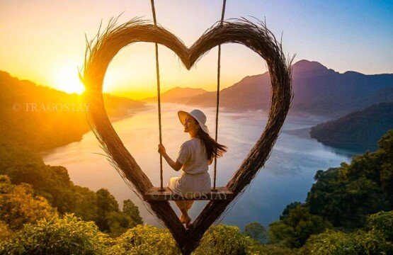 A young woman sitting inside a large heart-shaped wooden platform at Wanagiri Hidden Hills with the beautiful Lake Buyan in the background.