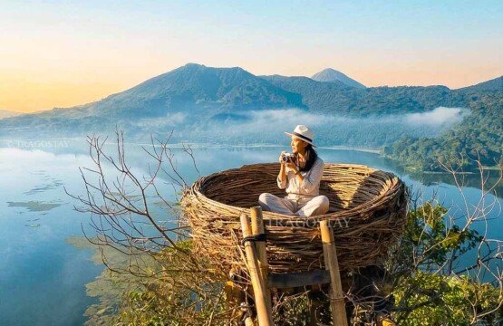 A female tourist sitting gracefully inside a large woven artificial bird's nest structure for a photo shoot at Wanagiri Hidden Hills.