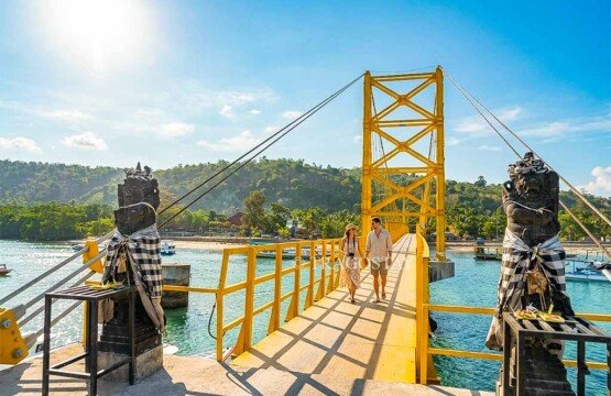 Two international travelers walking across the vibrant Yellow Bridge during a clear and bright morning.