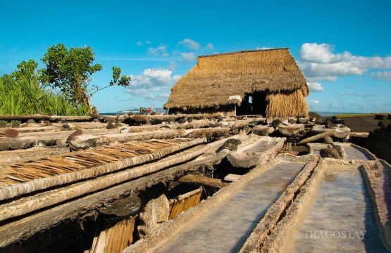 A row of rustic thatched-roof huts used for the traditional sea salt filtering and crystallizing process at Kusamba Beach.